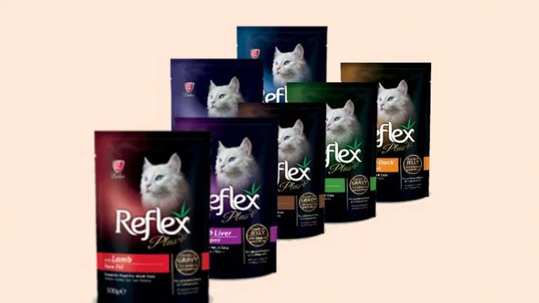 Sáu gói pate Reflex Plus nhiều vị xếp thành hàng trên nền kem